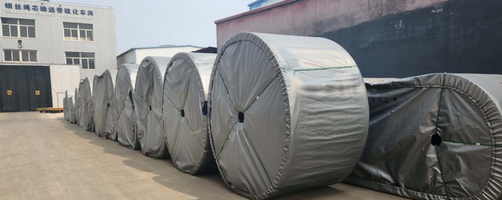 HUAXI RUBBER factory warehouse showing large stock of heavy-duty conveyor belt rolls ready for global shipment.